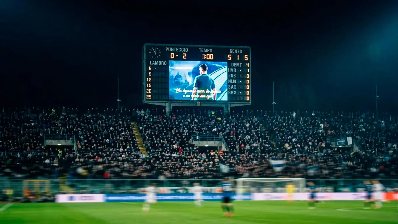 Tabellone luminoso di uno stadio con i gironi del Mondiale durante una partita serale